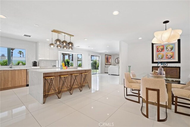 kitchen with decorative light fixtures, a center island, decorative backsplash, and white cabinetry