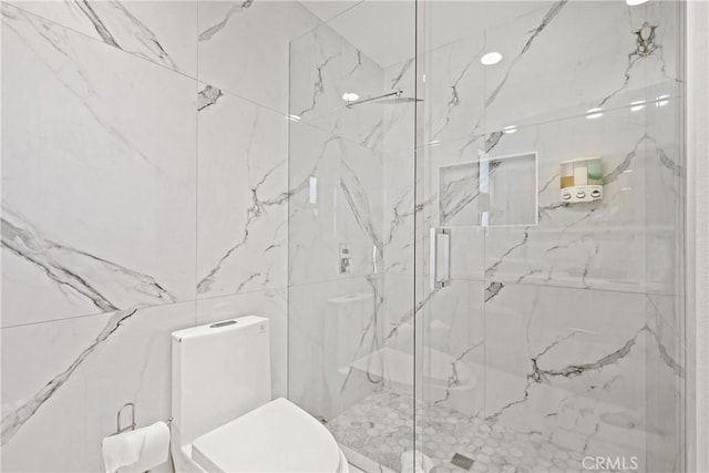 bathroom featuring toilet and a marble finish shower