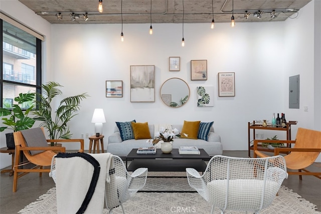 living room with electric panel, concrete flooring, and track lighting