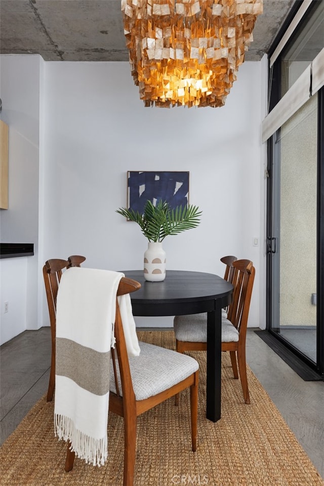 dining room featuring concrete flooring and a notable chandelier