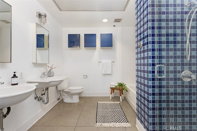 bathroom with tile patterned flooring, toilet, double sink, and tiled shower