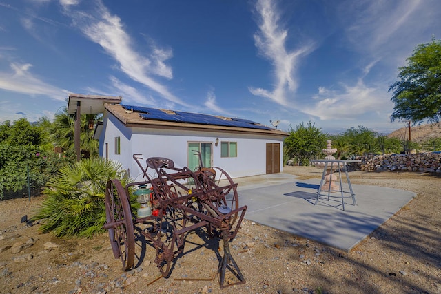 rear view of property featuring solar panels and a patio area