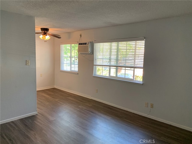 empty room featuring dark wood-type flooring, a wall mounted AC, a textured ceiling, and ceiling fan