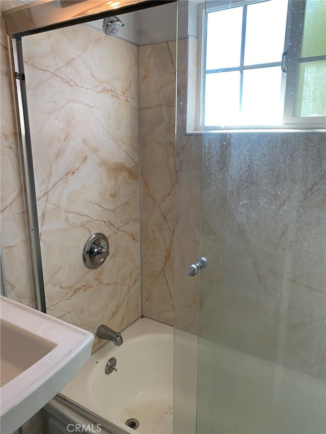 bathroom featuring combined bath / shower with glass door and sink