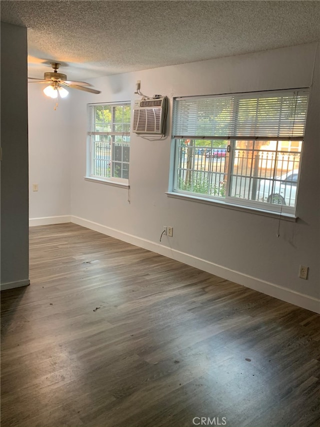 spare room featuring dark wood-type flooring, ceiling fan, a textured ceiling, and a wall unit AC