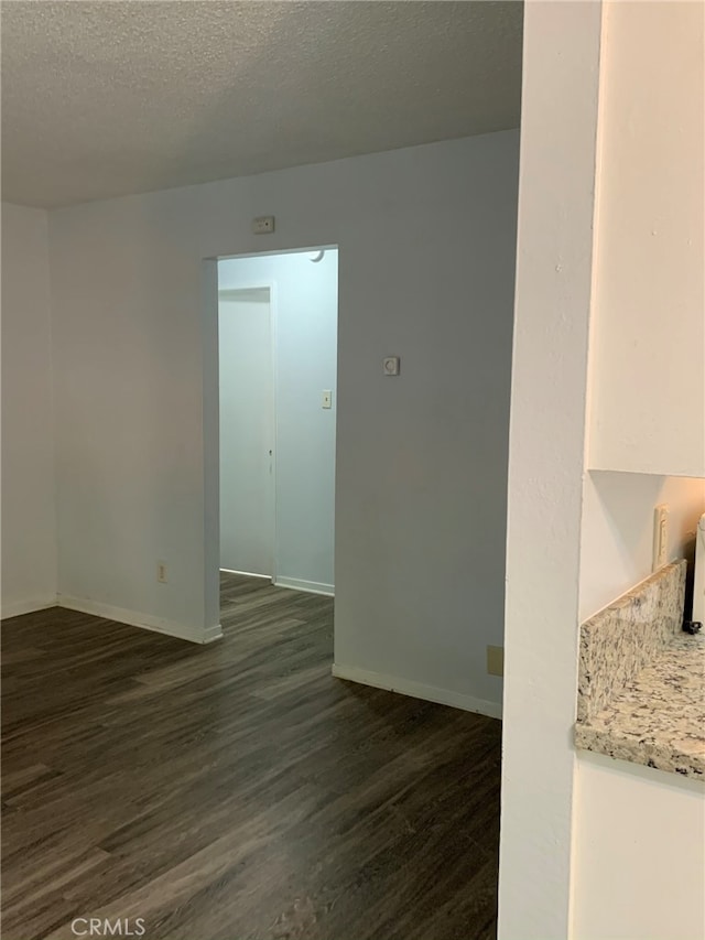 unfurnished room with a textured ceiling and dark wood-type flooring