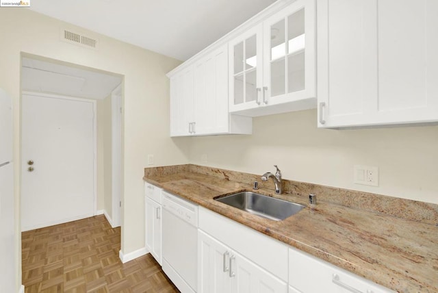 kitchen featuring white cabinets, light stone countertops, dishwasher, light parquet floors, and sink