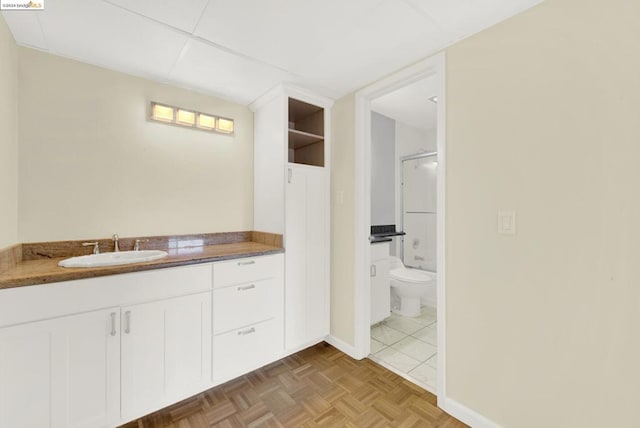 bathroom featuring vanity, toilet, tile patterned floors, and a shower with shower door