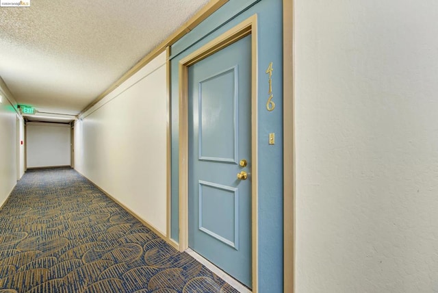 corridor with dark carpet and a textured ceiling