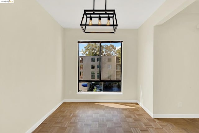 empty room featuring parquet flooring and a notable chandelier