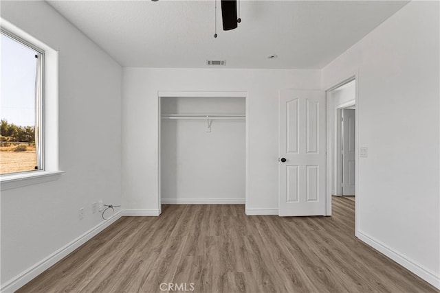 unfurnished bedroom featuring light hardwood / wood-style floors, a closet, a textured ceiling, and ceiling fan