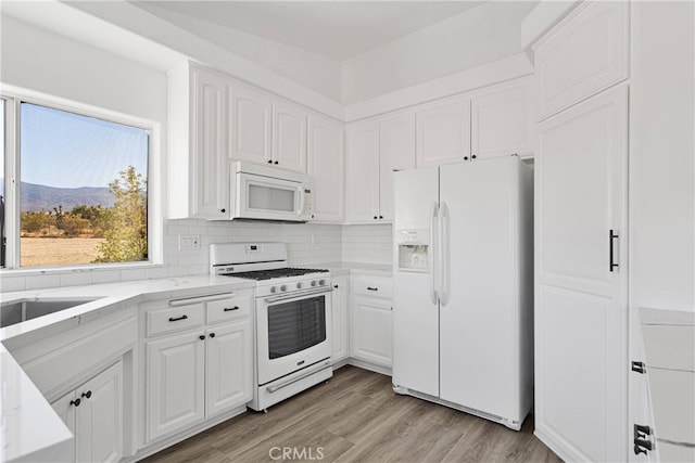 kitchen with white appliances, tasteful backsplash, white cabinetry, light hardwood / wood-style floors, and a mountain view