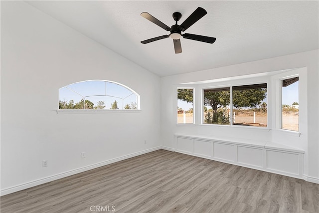 unfurnished room with a healthy amount of sunlight, ceiling fan, light wood-type flooring, and vaulted ceiling