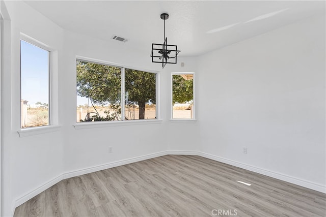 unfurnished dining area with a chandelier, light wood-type flooring, and a wealth of natural light