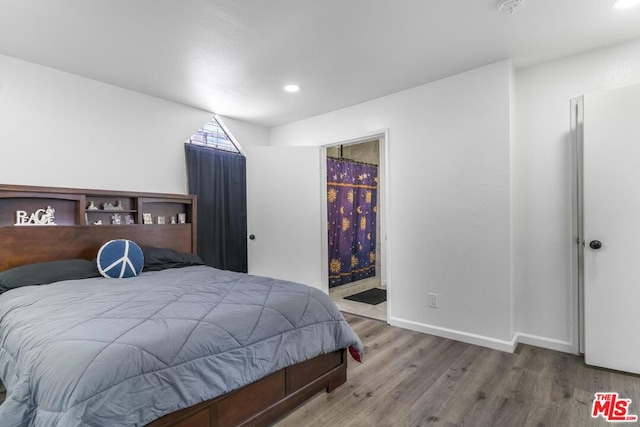 bedroom featuring connected bathroom and light hardwood / wood-style flooring