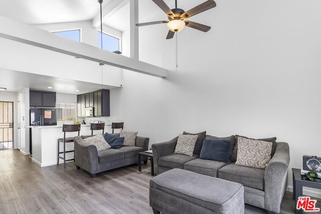 living room with ceiling fan, wood-type flooring, high vaulted ceiling, and beamed ceiling