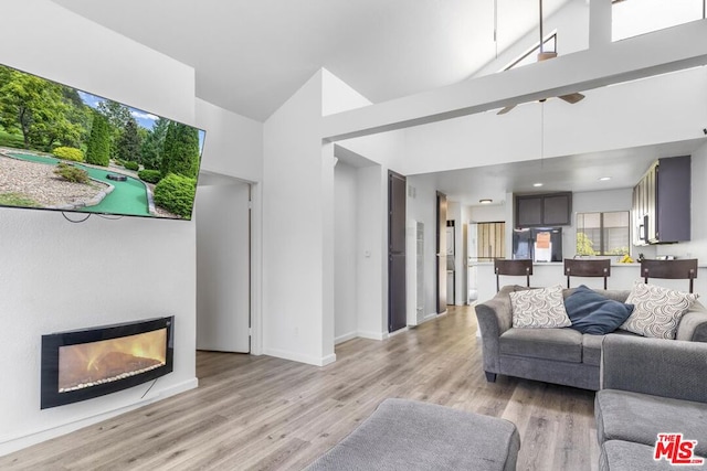 living room with a healthy amount of sunlight, a high ceiling, and light hardwood / wood-style flooring