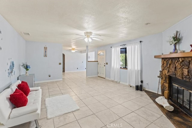 tiled living room with ceiling fan, a textured ceiling, and a fireplace