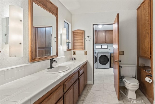 bathroom with vanity, toilet, and washing machine and clothes dryer