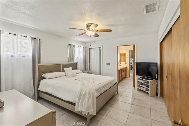 tiled bedroom featuring ceiling fan, a textured ceiling, and ensuite bathroom