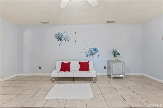 sitting room with a textured ceiling, light tile patterned flooring, and ceiling fan