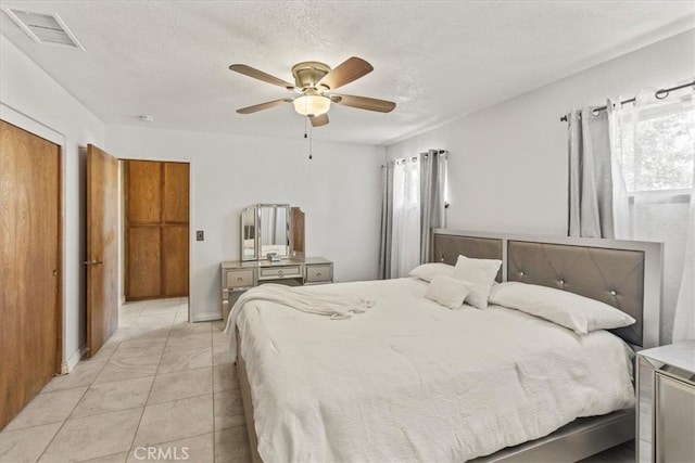 tiled bedroom featuring multiple windows, a textured ceiling, and ceiling fan