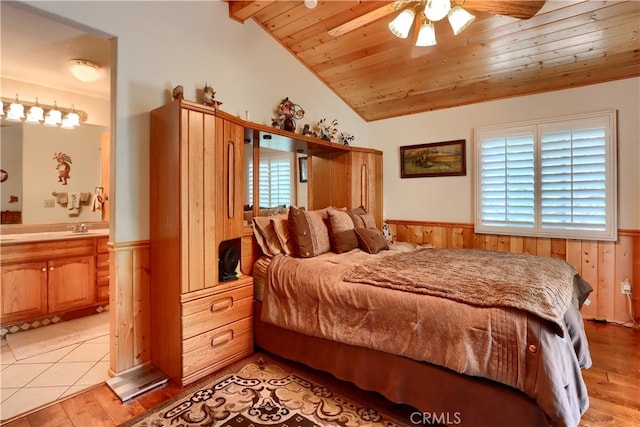 bedroom with vaulted ceiling with beams, wooden walls, wooden ceiling, light hardwood / wood-style floors, and ceiling fan