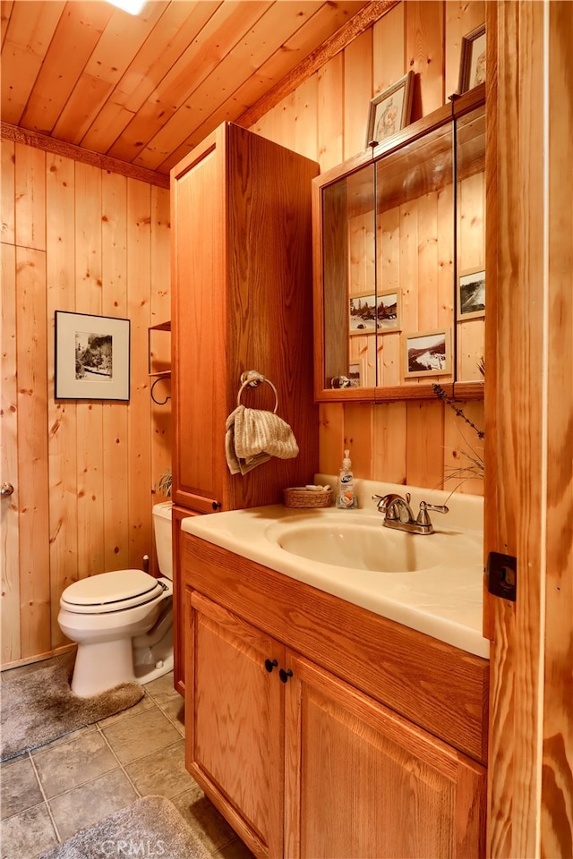 bathroom featuring toilet, wood ceiling, wood walls, and vanity