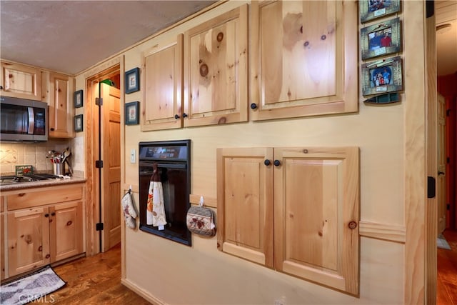 kitchen with appliances with stainless steel finishes, light brown cabinetry, backsplash, and dark hardwood / wood-style flooring