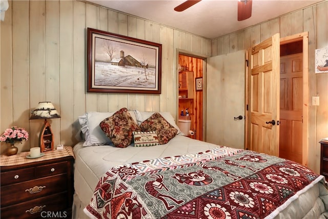 bedroom featuring ceiling fan and wooden walls