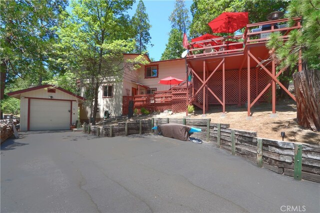 exterior space with a garage, a deck, and an outbuilding