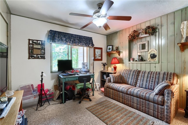 carpeted home office featuring wood walls and ceiling fan