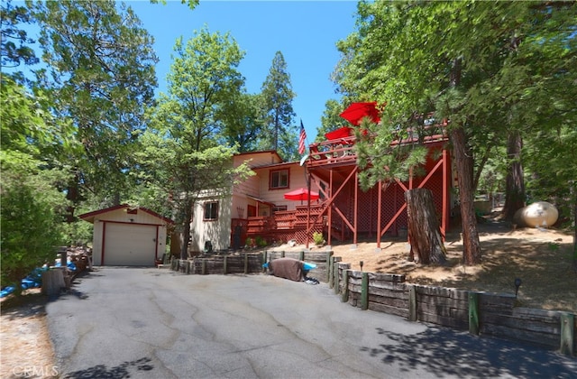 view of front facade with a garage, a deck, and an outbuilding