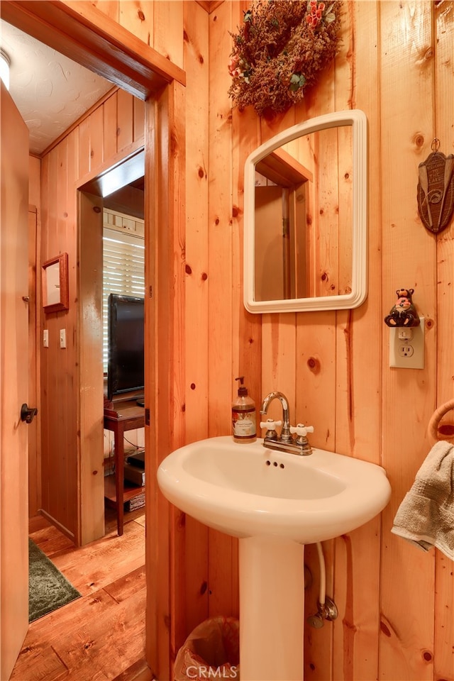 bathroom with wood walls, wood-type flooring, and sink