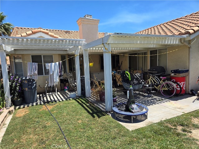 back of property featuring a pergola, a patio area, and a lawn