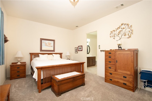 bedroom with ensuite bath and light carpet