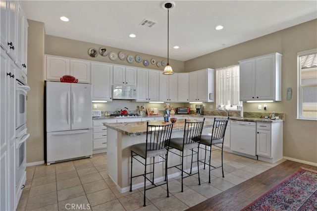 kitchen with a center island, white cabinets, light hardwood / wood-style flooring, and white appliances