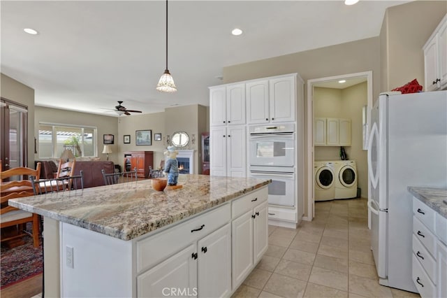 kitchen with white cabinets, decorative light fixtures, a kitchen island, and white appliances