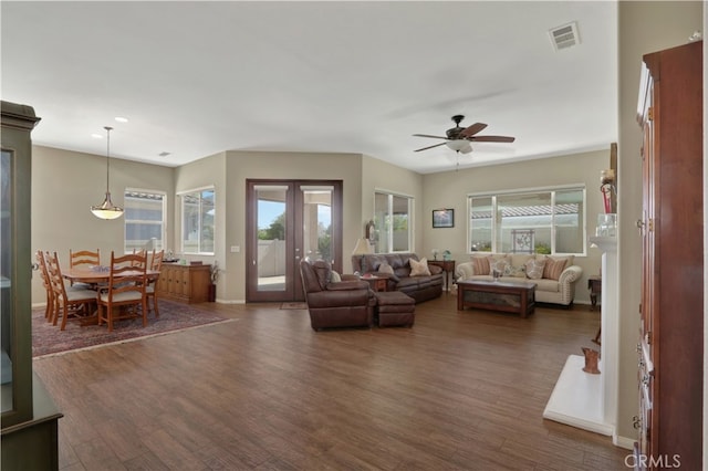 living room featuring dark wood-type flooring, ceiling fan, and plenty of natural light