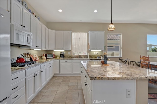 kitchen with a kitchen island, white cabinetry, pendant lighting, and white appliances