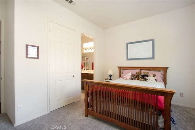 bedroom with light colored carpet and ensuite bath