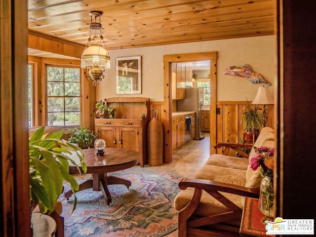 living area featuring an inviting chandelier, wood ceiling, and wood walls