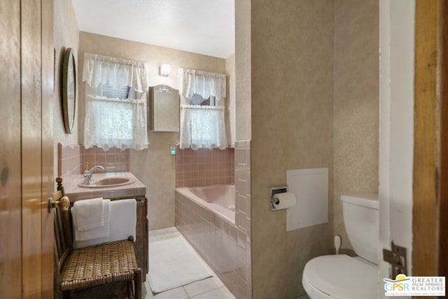 bathroom with vanity, tile patterned floors, tiled tub, and toilet