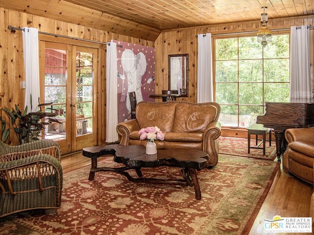 living area with french doors, wood ceiling, hardwood / wood-style flooring, and wooden walls