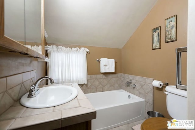 bathroom with a bathing tub, lofted ceiling, tile walls, toilet, and vanity