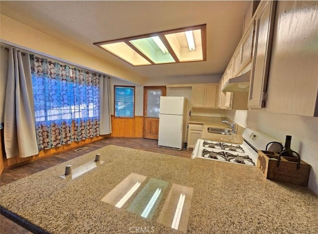 kitchen with white appliances, dark hardwood / wood-style floors, light stone counters, and sink