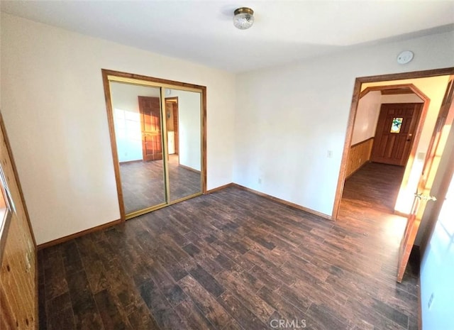 empty room featuring wooden walls and dark wood-type flooring