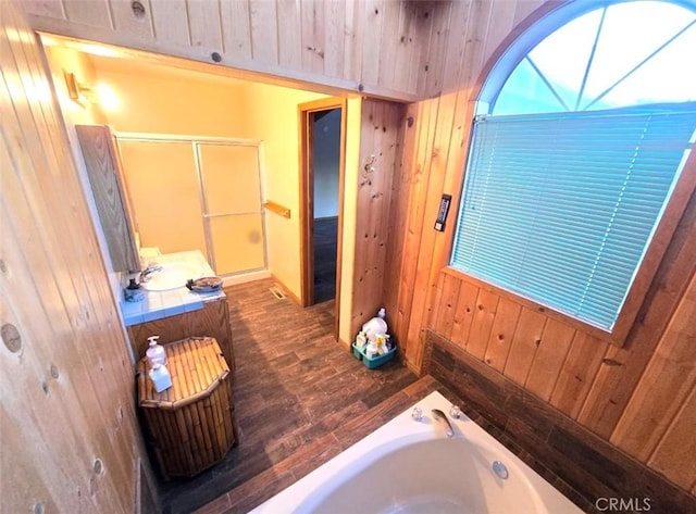 bathroom featuring wood walls, sink, plus walk in shower, and hardwood / wood-style flooring