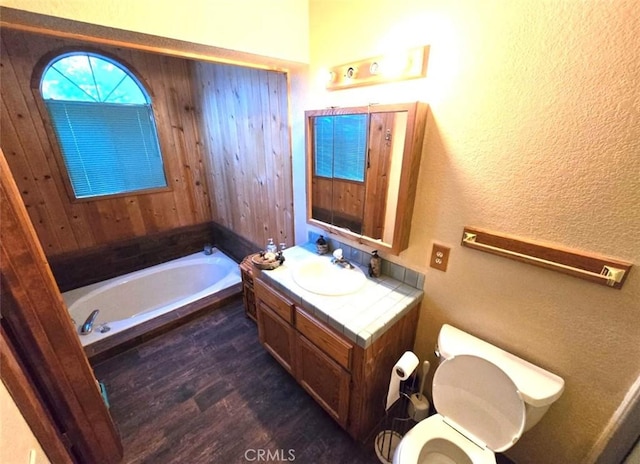 bathroom with a bathing tub, vanity, wood-type flooring, and toilet