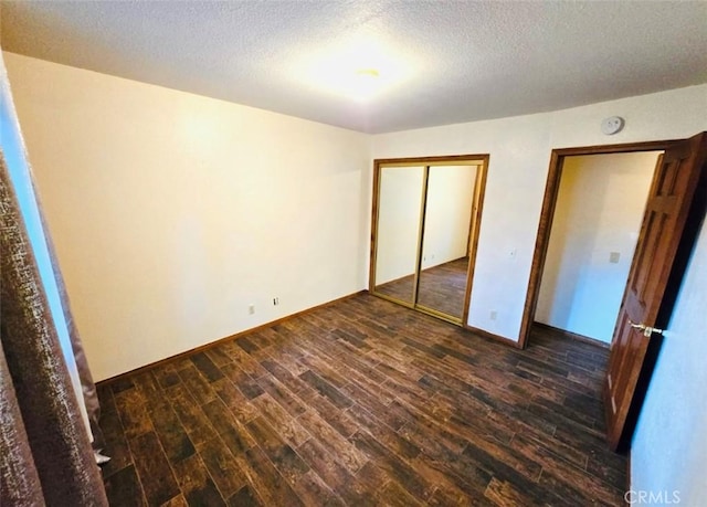 unfurnished bedroom with a textured ceiling and dark wood-type flooring